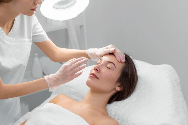 Schoonheidsspecialiste met vrouwelijke cliënt bij salon voor routine van de gezichtsverzorging