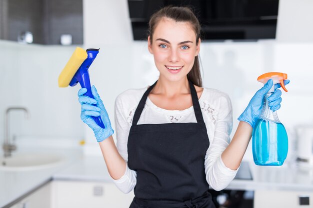 Schoonmaak concept. De jonge schoonmakende hulpmiddelen van de vrouwenholding in de keuken