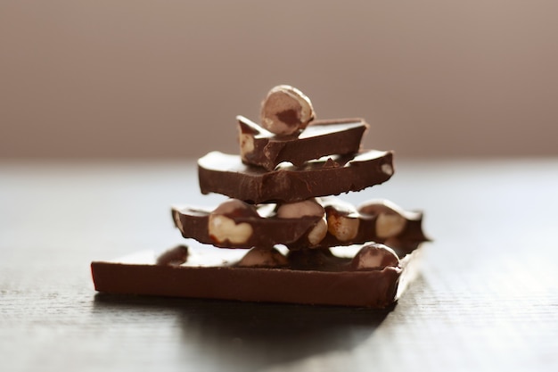 Schot van bruine tafel met chocolade, handgemaakte pyramide van chocholate stukken geïsoleerd over donkere ondergrond, melk chocholate met noten