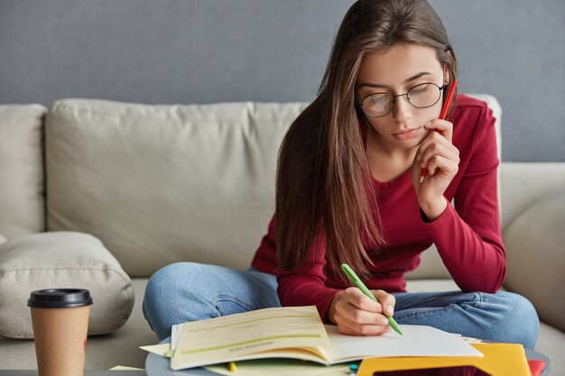 Schot van ernstige geschoolde student met pen in de hand, schrijft curriculum vitae