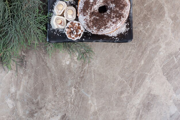 Schotel met Turkse lekkernijen en een donut op marmer.