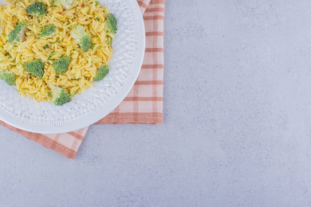 Schotel van gekookte bruine rijst met broccolibovenste laagje op marmeren achtergrond.