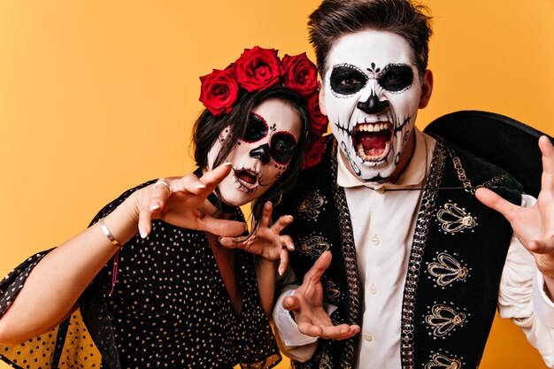 Schreeuwende Mexicaanse man en zijn vriendin met Halloween-make-up beangstigend poseren voor portret.