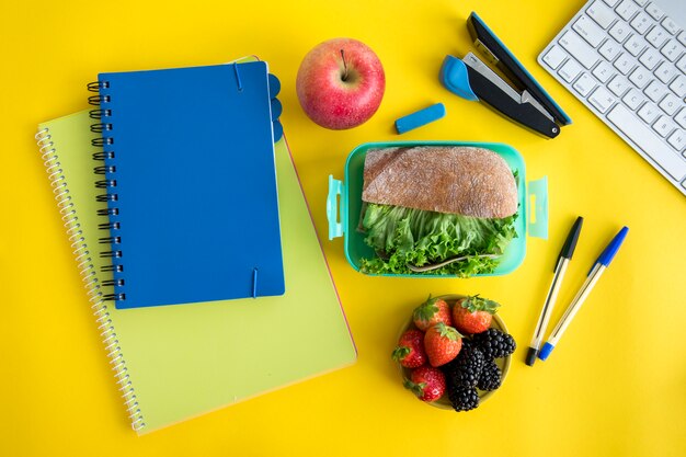 Schrijfboeken, lunchbox en briefpapier op tafel
