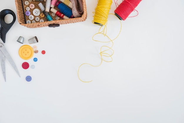 Scissor; toetsen; vingerhoed; rood en geel garen geïsoleerd op een witte achtergrond