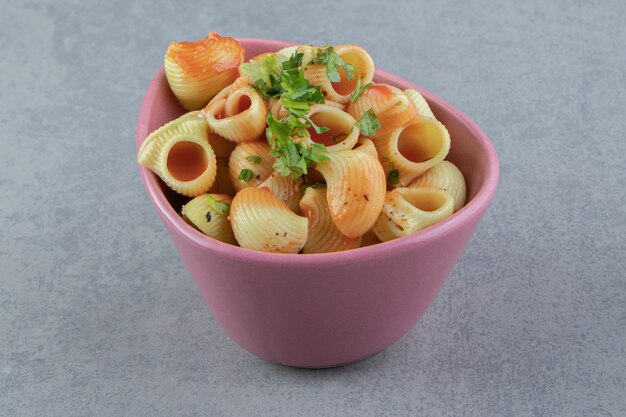 Seashell pasta met saus in roze kom.