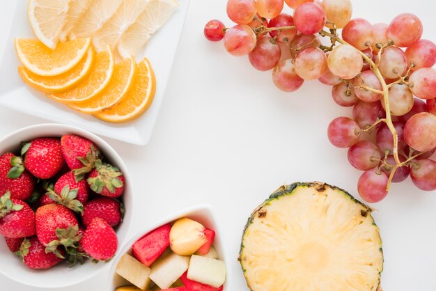 Segmenten van citrusfruit; aardbei; ananas; watermeloen en druiven op witte achtergrond