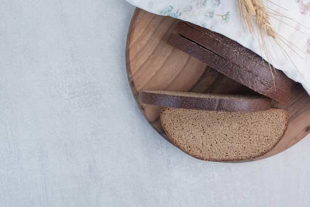 Segmenten van vers bruin brood op een houten bord.