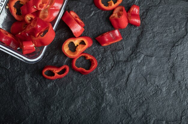 Segmenten van zoete rode paprika op zwart.