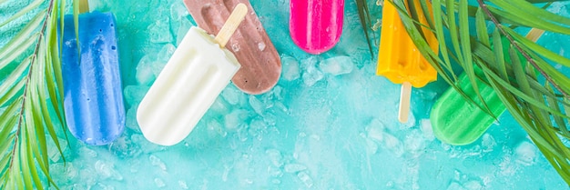 Selectie van heldere veelkleurige ijslolly. diverse gelato, bevroren lolly's - chocolade vanille bosbes aardbei pistache sinaasappel, met gemalen ijs op lichtblauwe zonnige achtergrond