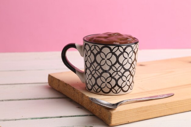 Selectieve aandacht shot van een kop warme chocolademelk op een houten bord met een roze achtergrond