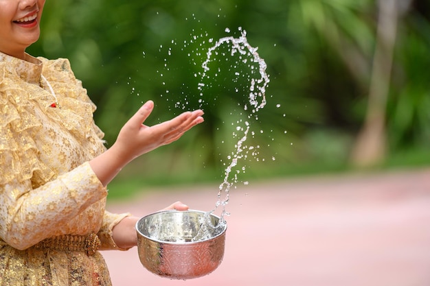 Gratis foto selectieve focus en close-up vrouwelijke hand met waterkom en opspattend water in tempels en behoud de goede cultuur van thaise mensen tijdens songkran-festival thai new year family day in april