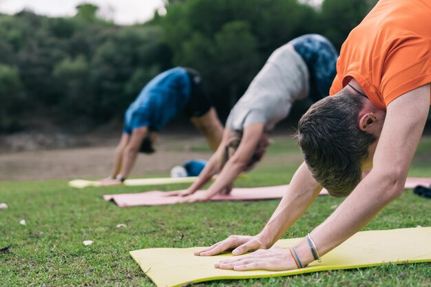 Selectieve focus op de eerste van drie man die yoga doet in een park