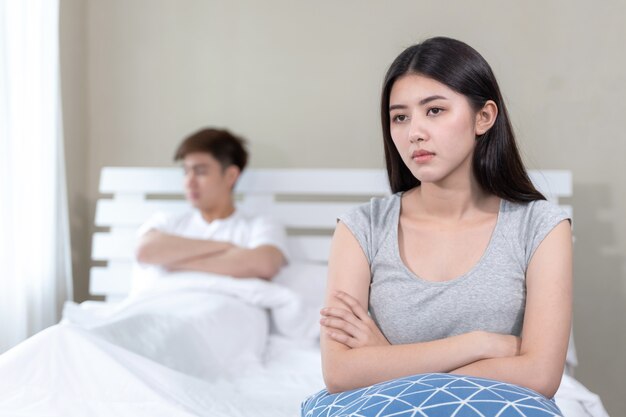 Selectieve jonge vrouw zittend op bed met verveeld gevoel over haar man