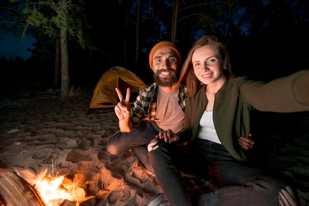 Selfie van paar die bij nacht door kampvuur kamperen