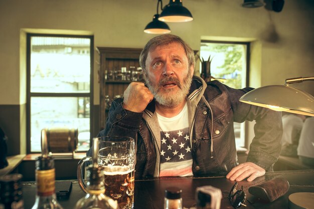 senior bebaarde man bier drinken in de pub