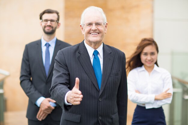 Senior business man met een opgeheven duim omhoog glimlachen