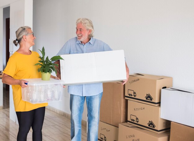 Senior gelukkige paar met verhuisdozen die het nieuwe lege appartement binnenkomen - concept van actieve ouderen en een nieuw begin zoals gepensioneerd