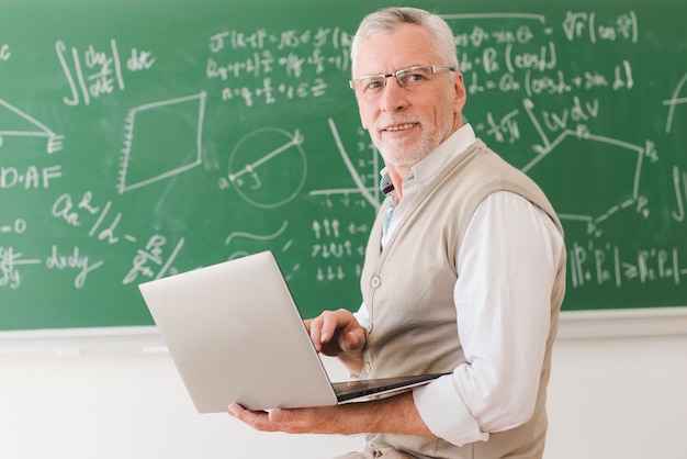 Senior hoogleraar typen op laptop in de klas