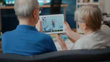 Gratis foto senior koppel woont online ontmoeting met arts bij op digitale tablet, doet thuis consultatie op afstand. oudere mensen die videoconferentie gebruiken, doen een beroep op een moderne gadget voor internet-telegeneeskunde.