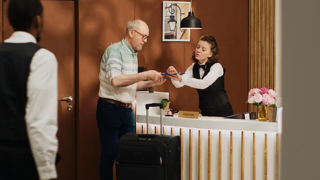 Senior man bij de receptie doet het inchecken