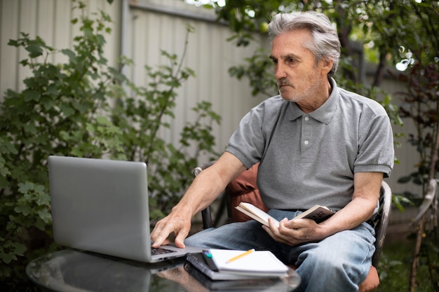 Senior man doet online lessen op een laptop