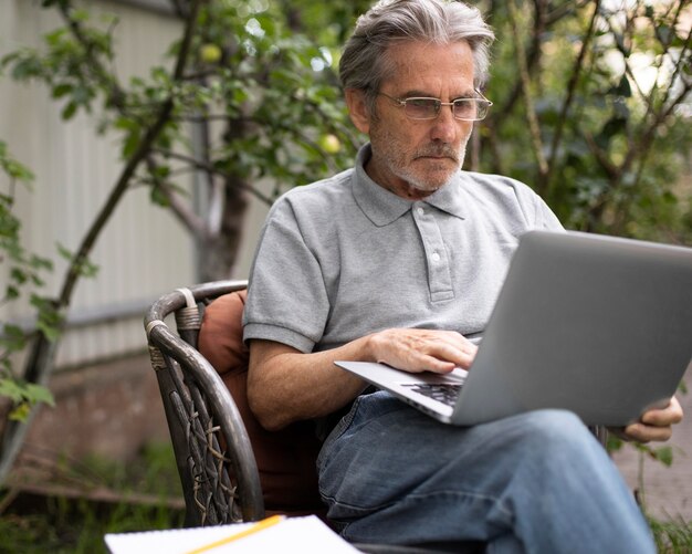 Senior man doet online lessen op een laptop