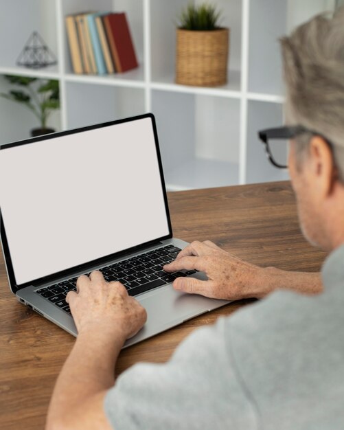 Senior man doet online lessen op een laptop