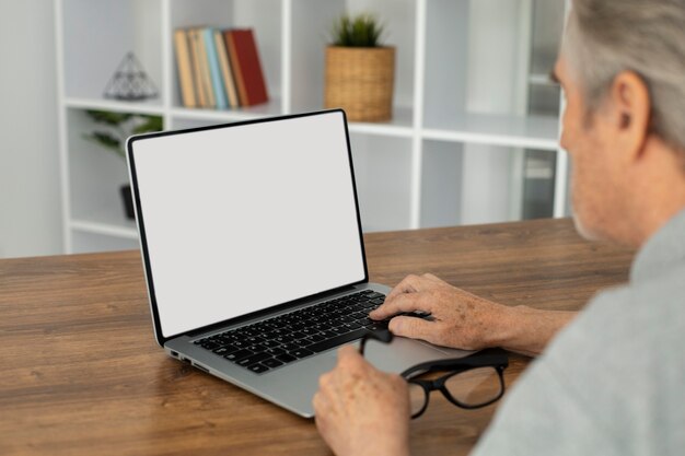 Senior man doet online lessen op een laptop