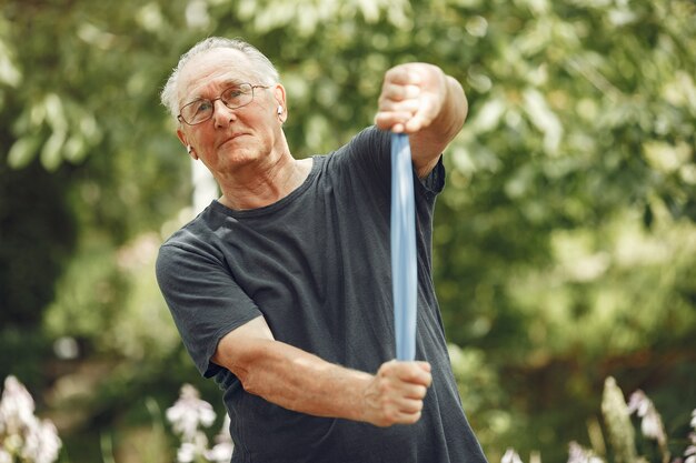 Senior man in zomer park. Grangfather gebruikt een eraiser.