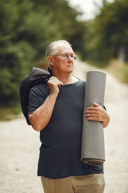 Senior man in zomer park. Grangfather met een mat.