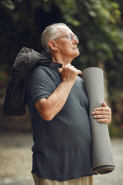 Senior man in zomer park. Grangfather met een mat.