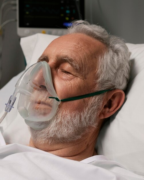 Senior man met beademingsapparaat in een ziekenhuisbed