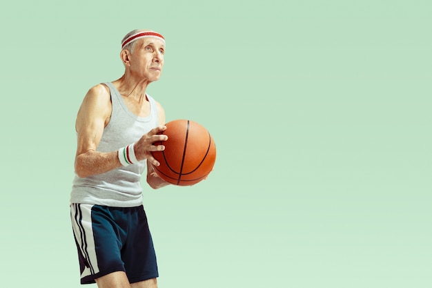 Senior man met sportwear basketbal spelen op groen