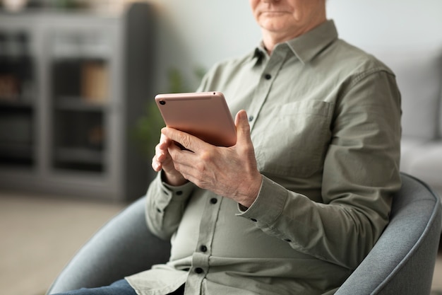 Senior man met tablet zittend op de bank in de woonkamer