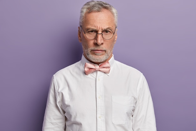 Senior man met wit overhemd en roze bowtie