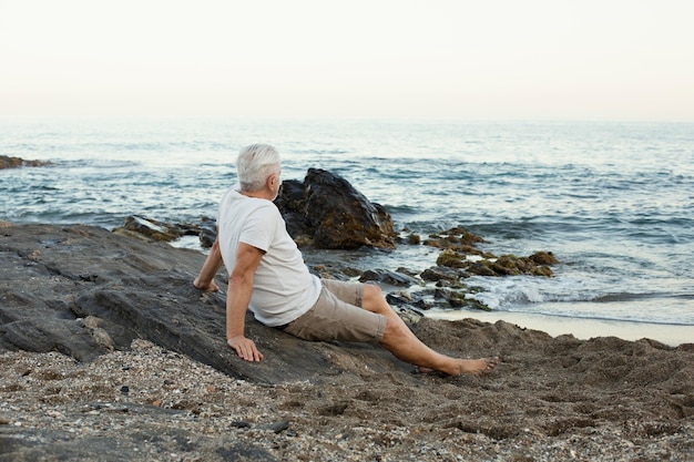 Senior man rust op het strand en bewondert de oceaan