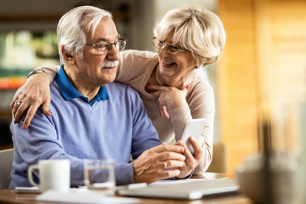 Gratis foto senior man sms'en op mobiele telefoon terwijl vrouw thuis met hem praat