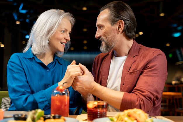 Senior man verrast zijn vriend en houdt haar handen vast in een restaurant
