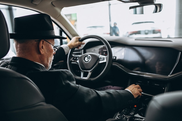 Senior man zit in een auto