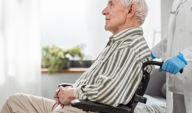 Senior man zit in een rolstoel naast een arts