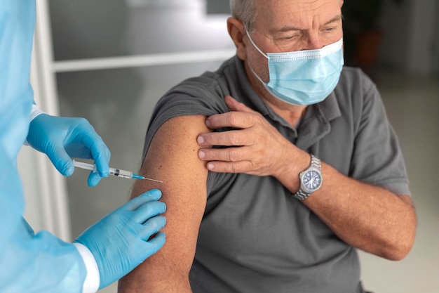 Gratis foto senior mannelijke patiënt die wordt gevaccineerd tegen coronavirus