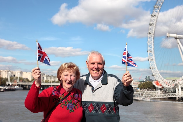 Senior paar bedrijf Britse vlag in Londen met Millenium wiel