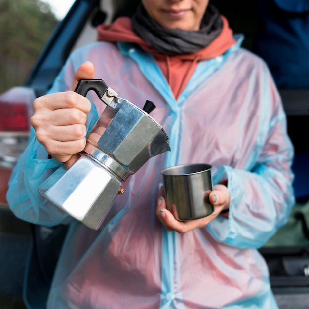 Senior toeristische vrouw gieten koffie in metalen mok