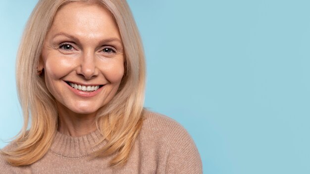 Senior vrouw die lacht tegen een blauwe achtergrond