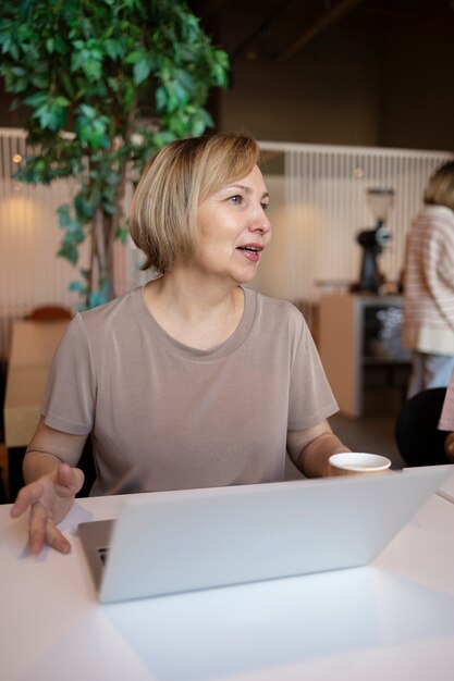 Senior vrouw die op haar laptop werkt in een café