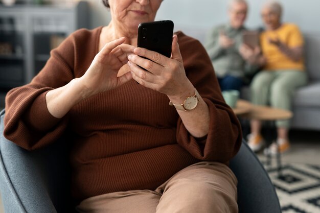 Senior vrouw die smartphone gebruikt die thuis in de woonkamer zit