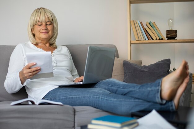 Senior vrouw die thuis een online les volgt op haar laptop