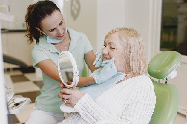 Senior vrouw met tandheelkundige behandeling op het kantoor van de tandarts. De vrouw wordt behandeld voor tanden