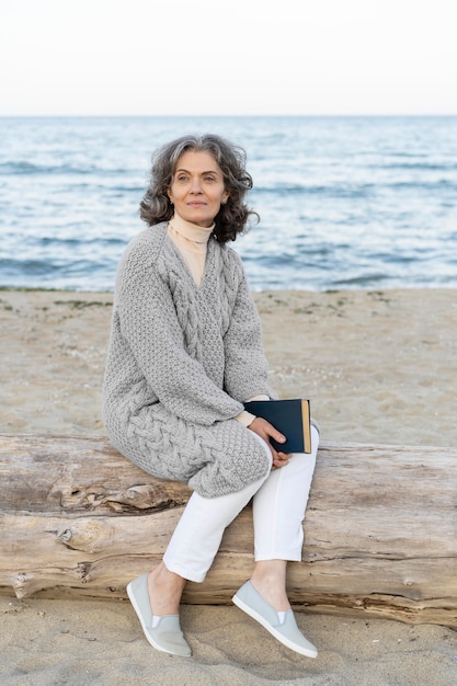 Gratis foto senior vrouw op het strand met een boek